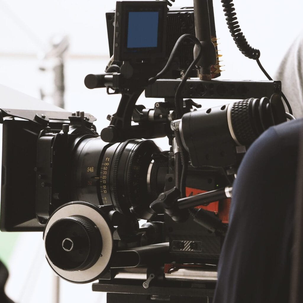 Behind the shooting or filming video movie and film production crew team setting up camera on tripod and professional equipment in studio for offline tv commercial or online web film recording.